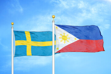 Sweden and Philippines two flags on flagpoles and blue sky