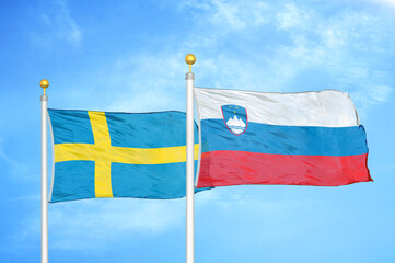 Sweden and Slovenia two flags on flagpoles and blue sky