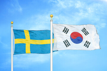 Sweden and South Korea two flags on flagpoles and blue sky