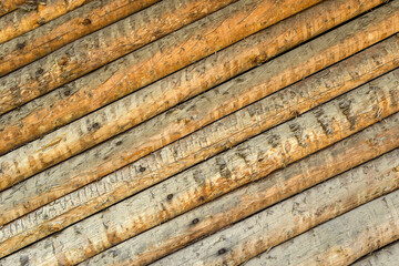 Diagonal wooden logs with texture and wood knots. Fragment of unpainted and planed barn wood wall for desktop wallpaper or background