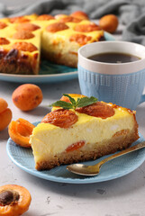 Cheesecake with apricots with a cut out piece, located on a blue plate and cup of coffee, vertical format, Closeup
