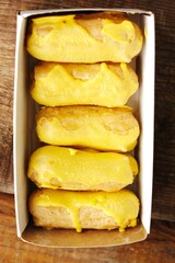 Delicious eclairs with yellow glaze in a box 