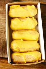 Delicious eclairs with yellow glaze in a box 
