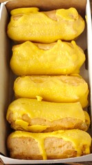 Delicious eclairs with yellow glaze in a box 