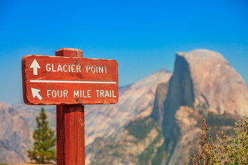 AMERICAN SUNSET: wooden road sign of Glacier Point trail in Yosemite National Park, California, United States. The view from Glacier Point: Half Dome and Clouds Rest in Yosemite Valley. - Powered by Adobe