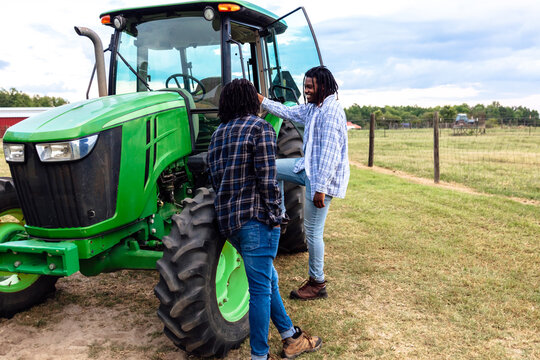 Brothers chatting next to tractor on farm
