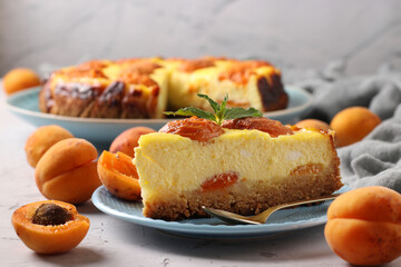 Homemade cheesecake with apricots on light gray background, horizontal format, close-up
