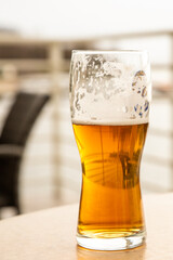 a glass of cold lager light beer, lunch in a summer cafe on a blurred background of the river