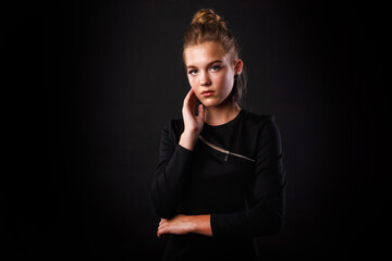Fashion glamorous portrait of a girl in black dress on dark background. Elegant hairstyle, bright makeup and lip color.