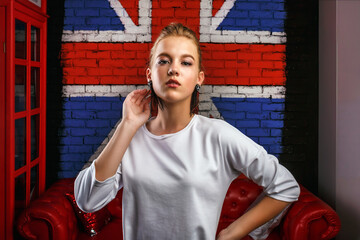 Fashion glamorous portrait of a girl model with white sweater on wall background with a British flag