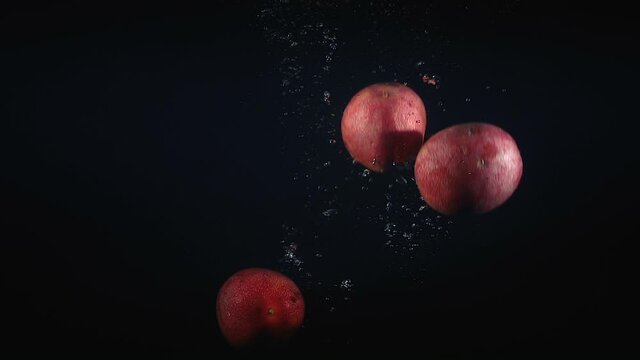 Footage of falling maracuya in the water on black background