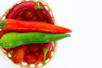 pair spicy vegetable pepper green red pod seasoning asia parallel horizontal on a basket of tomatoes white isolated background