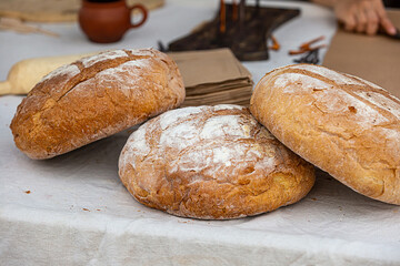 fresh baked bread with brown crust lies on a table covered with a linen tablecloth