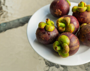 fresh round fruit mangosteen delicious lies on a plate standing on a transparent table