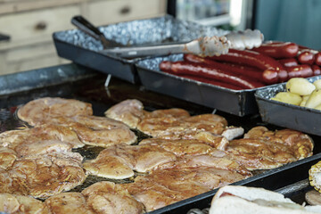 buffet assortment of dishes a piece of raw chicken steak seasoned with pepper, spicy grilled sausages