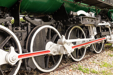 the wheels of the locomotive are large black with white rims standing in the tracks
