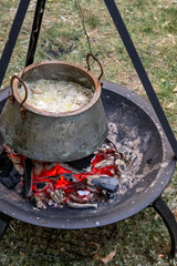 bowler full of soup brewed over a fire cooking on an open fire while camping