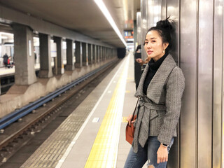 Beautiful young woman with smiling waiting a train at subway station