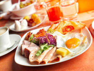 Delicious breakfast served with coffee, orange juice, egg, ham, salad, bacon rolls at the luxury hotel