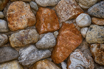 background stone wall solid and weathered folded from brown and gray cobblestone closeup