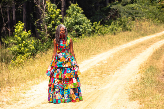 Pretty woman with locs wearing colorful African dress on rural farm