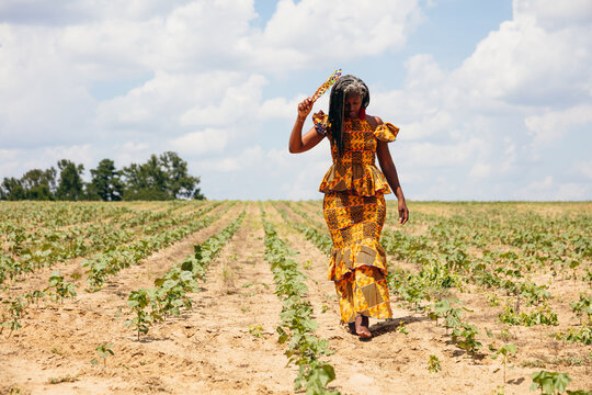 Woman walking cotton field in pretty African dress