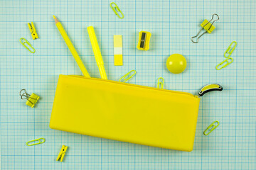 bright yellow school pencil case and stationery on scaled coordinate paper. school educational concept