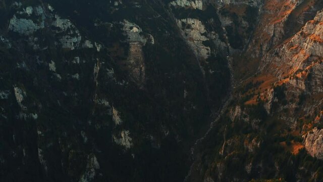 Aerial view on rocky peak mountains. Video from drone flying over valleys, forested and cliffs slopes of the mountain range. Sunset time in Romania, Majestic landscape, travel background, 4k