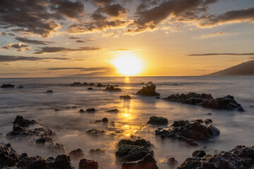 Low angle  Sunset on beach in Hawaii Maui Long exposure of waves coming in.