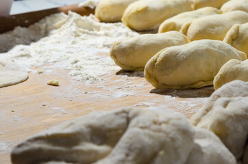 Fototapeta na wymiar Dough on a Board with flour and pies. Cooking homemade hotcakes with onion and egg filling.