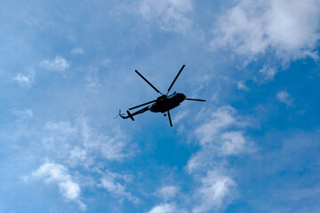 Fototapeta na wymiar helicopter in the blue cloudy sky from beneath