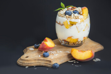 Healthy blueberry, peach and walnut parfait in a glass on a dark background