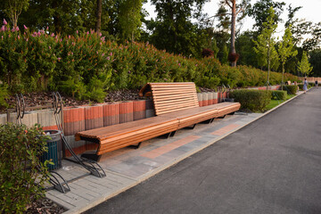 Fototapeta premium Large empty wooden brown bench in summer park