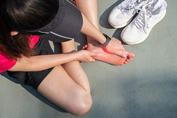 Top view of runner woman suffering from injury and she trying to do foot massage by herself. A foot...