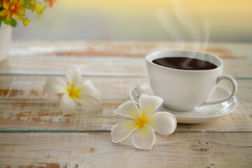 Fototapeta na wymiar Plumeria flowers with Espresso or americano, black coffee cup on a wooden floor