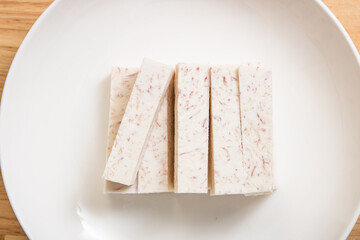 A dish of neatly cut taro pieces on a wood-grain table