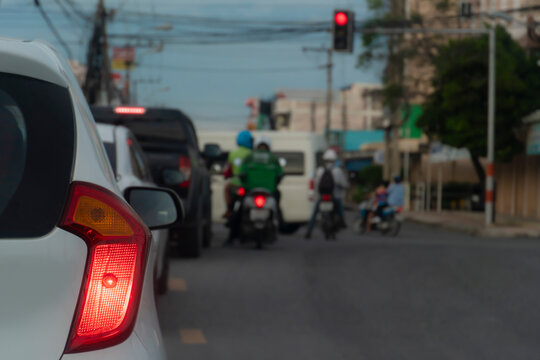 Close up of car rear light stop and wait for the traffic lights at the intersection.  With blurry images of cars and motorcycles waiting in the queue in front.