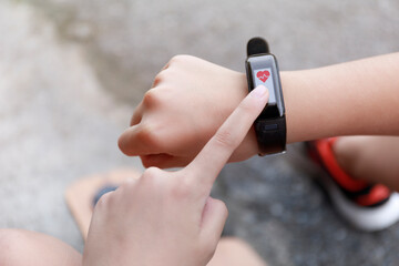 Close up Girl using smartwatch touching button and touchscreen on active sports. Finger touch button on smarth watch. Girl set smart watch before running on road.