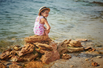 A little girl is resting on the sea coast . Children's health holidays at the sea resort