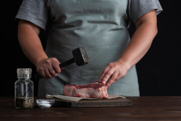 Chef chops meat entrecote with a special hammer