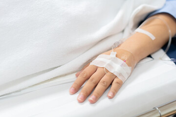 Close up of saline solution on hand of a patient in clothes lying on the hospital bed, Patient is on a drip receiving a saline solution.