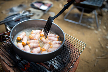Breakfast for all ages,Pigs in Blankets or Mini sausages wrapped in smoked bacon on a hot frying pan on a charcoal grill at camping,simple food in the kitchen for traveling during in the morning
