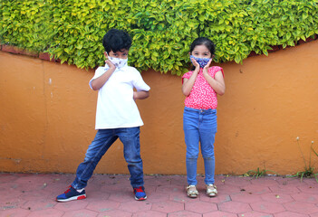 6-year-old boy and girl with protective face masks for virus covid-19, in the park, new normal