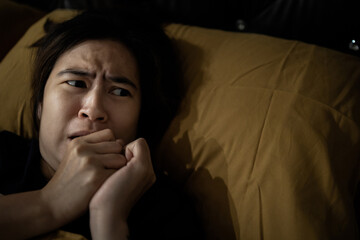 Frightened woman is looking around while lying on her bed,feeling anxious,afraid of shaking,hearing something haunting,symptoms of phobia,hallucinations,sleep deprivation or insufficient sleep chronic