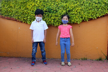 6-year-old boy and girl with protective face masks for virus covid-19, in the park, new normal