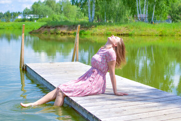 beautiful woman in dress on the lake in summer dreaming, relaxed vacation