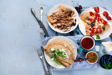 Variety of homemade crepes on grey background.