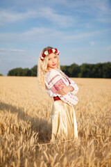 Young white woman with long blondy hair dressed a white dress in a wheat field