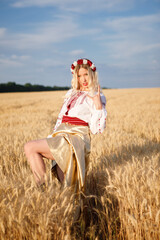 Young white woman with long blondy hair dressed a white dress in a wheat field