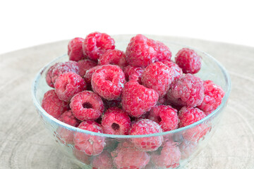 Raspberry berries in a plate on the table on a white background.	